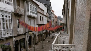 Una stretta via fiancheggiata da edifici, con balconi e ringhiere decorative.