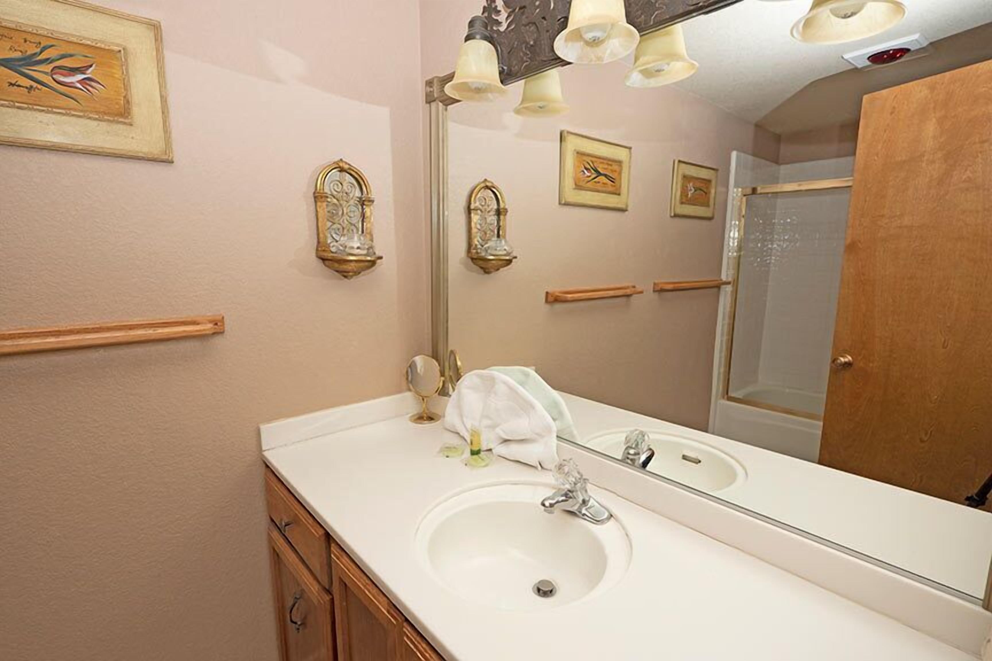 Une salle de bain avec un lavabo blanc, un grand miroir et des appliques murales.