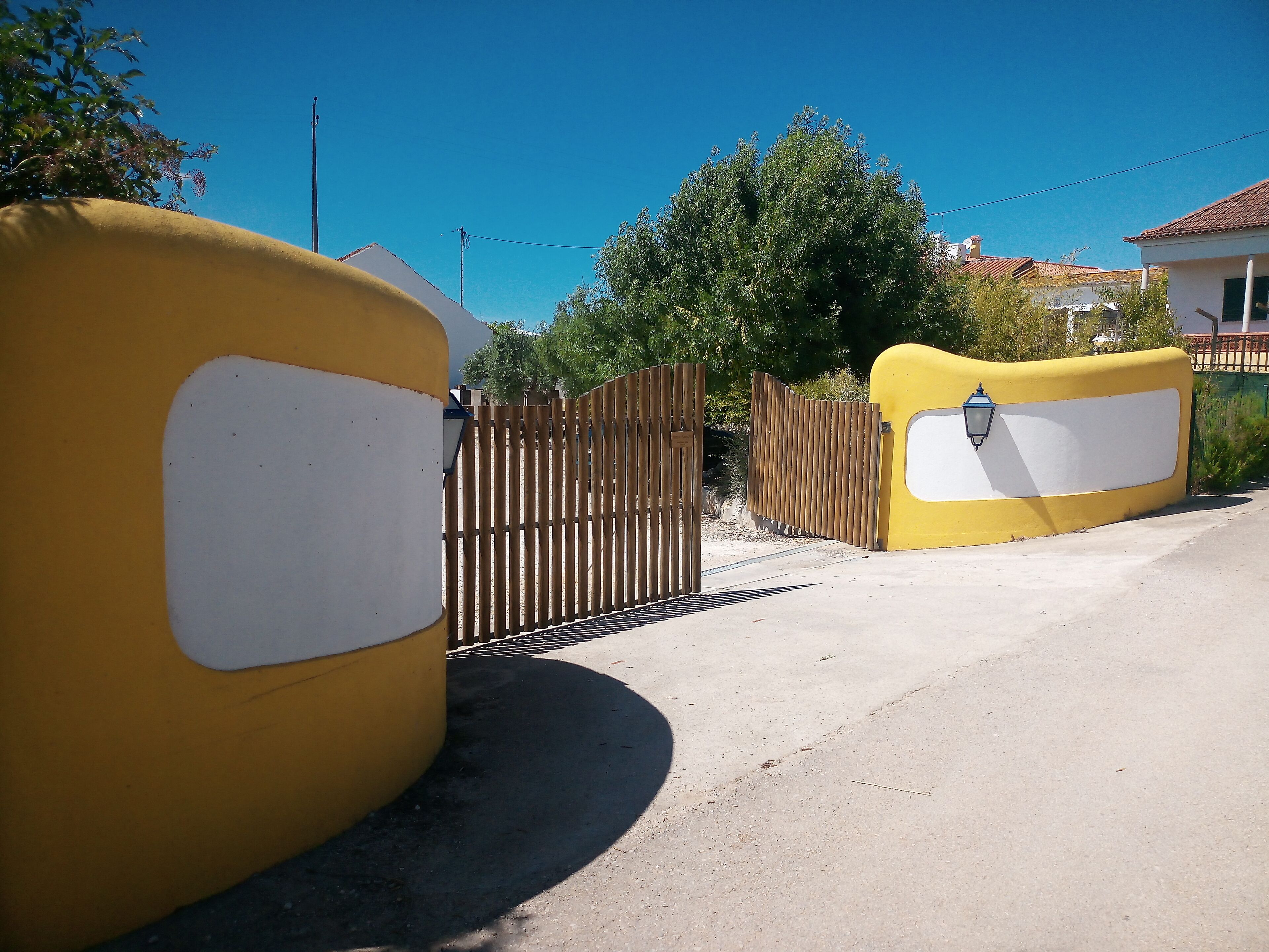 Una entrada cerrada con un muro amarillo y una valla de madera.