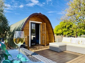 A wooden cabin with a curved roof, a glass door, and a deck with outdoor furniture. - Turquoise House & have fun at Villa Campus (Santarém)