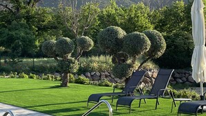 Une piscine dotée d’une terrasse carrelée, entourée d’une pelouse bien entretenue et de plusieurs chaises longues.