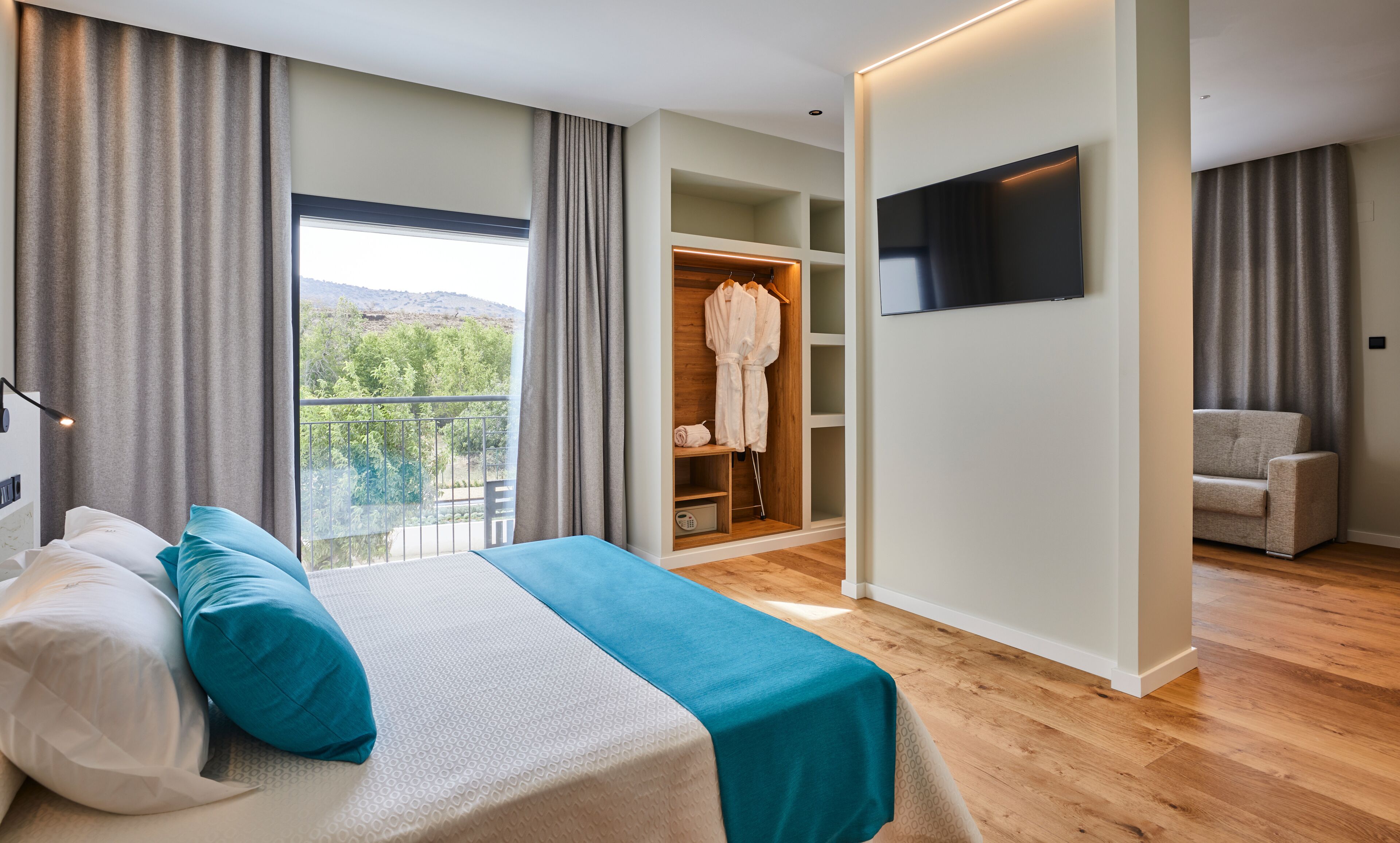 Un dormitorio con cama, televisor, armario y balcón.