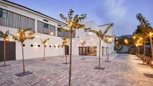 Une cour avec un chemin pavé, des guirlandes lumineuses et de petits arbres.