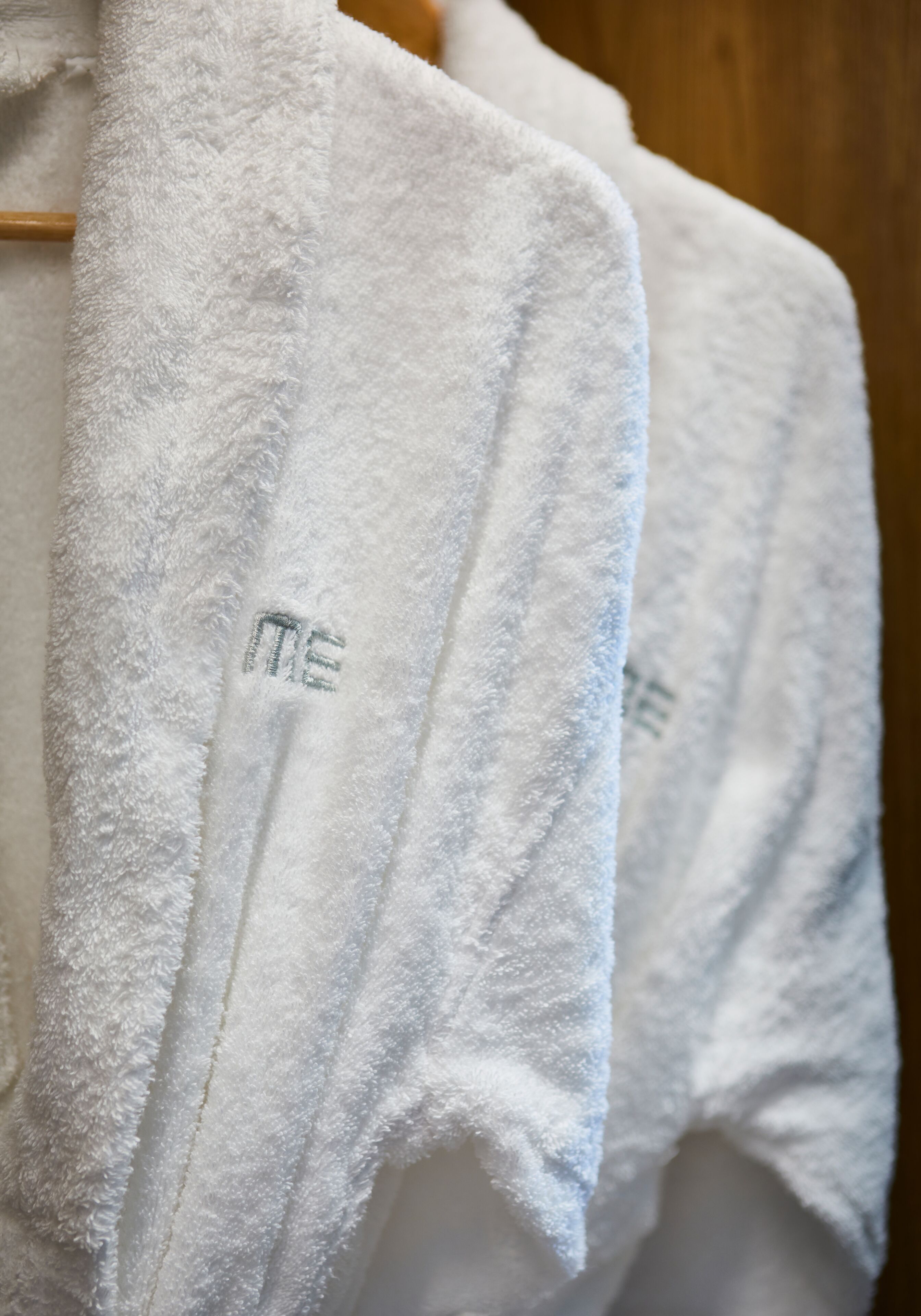 A row of white towels with embroidered text on a wooden rack.
