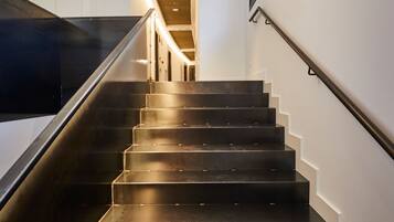 A modern staircase with a sleek design, leading to a landing area with a framed picture on the wall.
