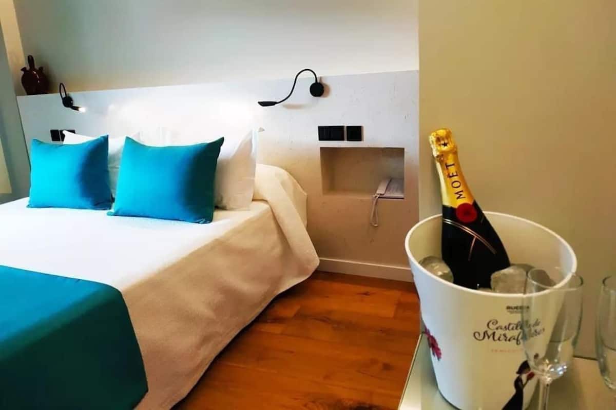 Een hotelkamer met een bed, nachtkastje, een fles champagne en een glas.