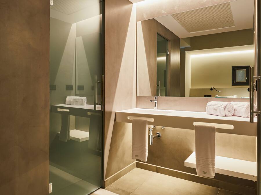 A modern bathroom with a glass shower enclosure, a large mirror, and a vanity with a towel rack.