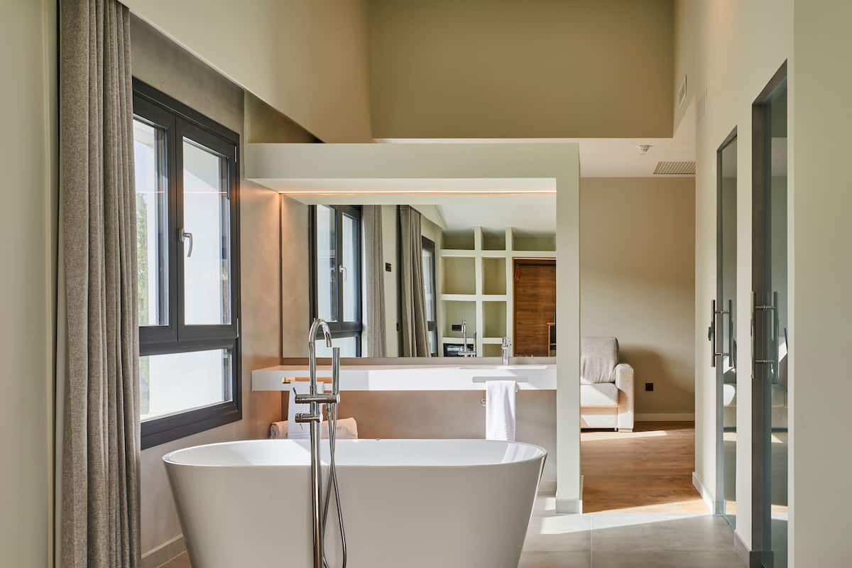 Een moderne badkamer met een vrijstaand bad, een grote spiegel en een houten vloer.