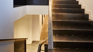 Un escalier moderne avec une rampe métallique élégante, un luminaire original et une grande fenêtre sur le côté droit.