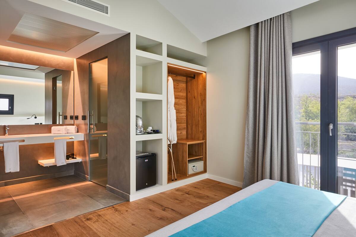 Een moderne badkamer met een inloopdouche, een wastafel met spiegel en een groot raam met uitzicht op de omgeving.