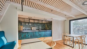 Un intérieur moderne avec un bar, des sièges et une vue sur l’extérieur grâce à une grande fenêtre.