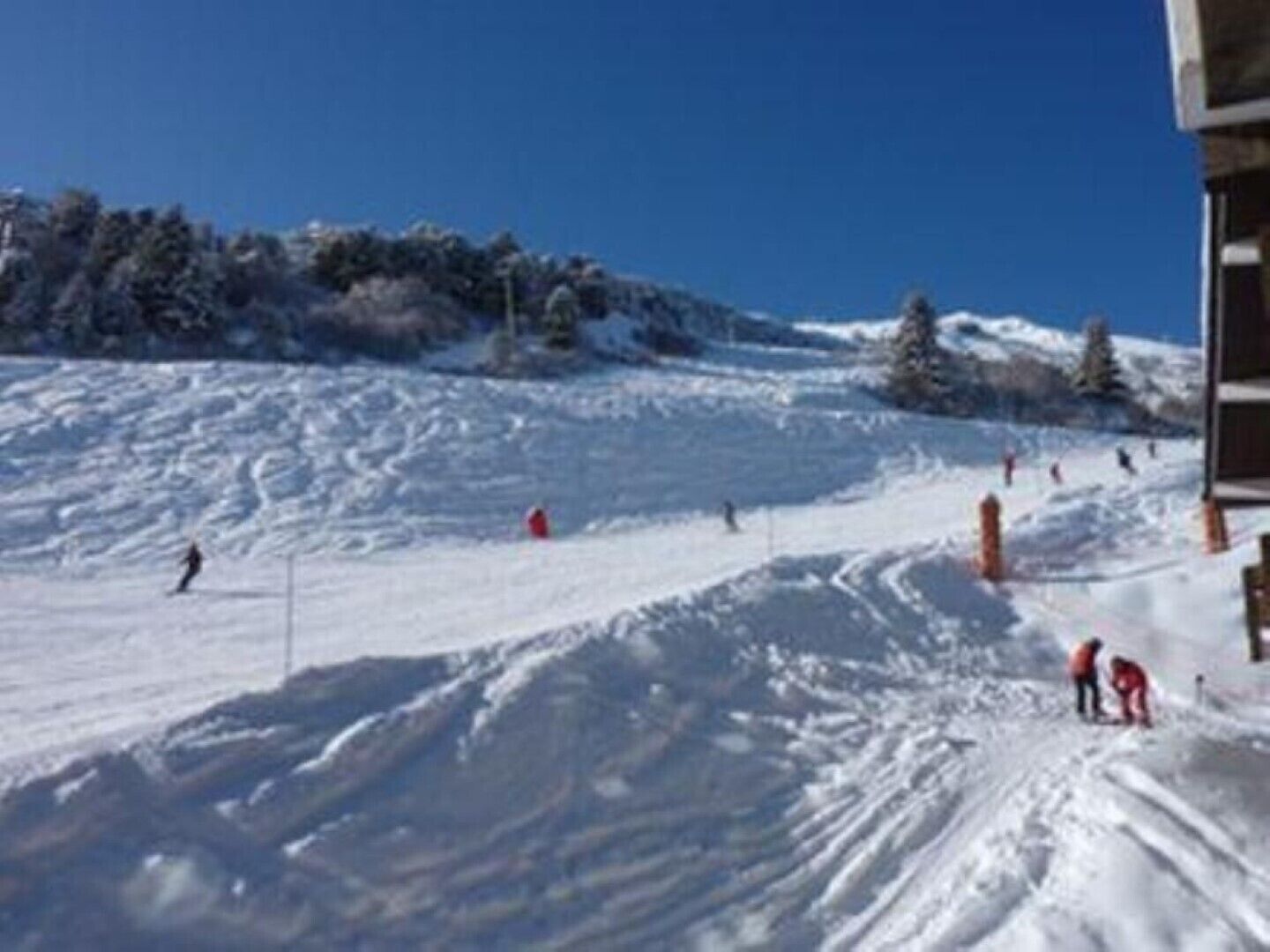 En ski bakke med skiløbere og en hytte i baggrunden.
