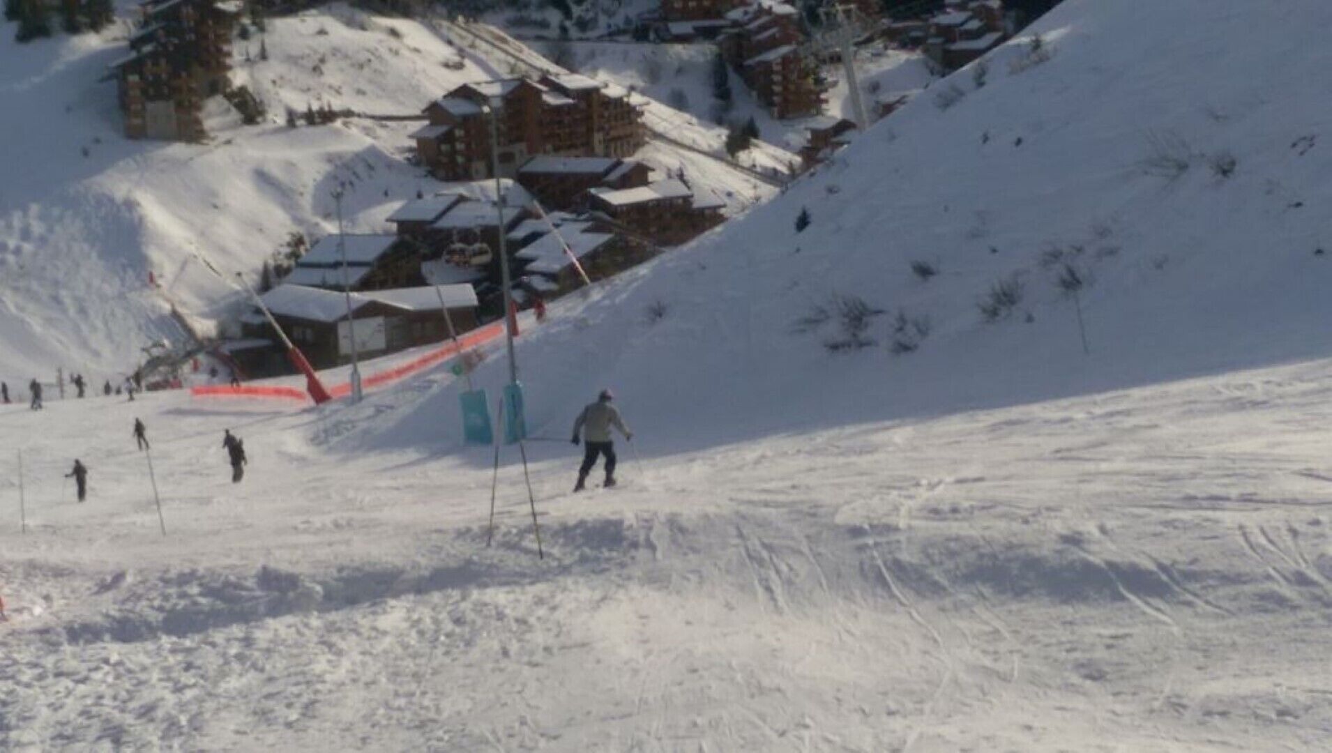 Una pista de esquí nevada con edificios al fondo.