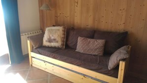 A wooden sofa with cushions in a room with wooden walls and a radiator.