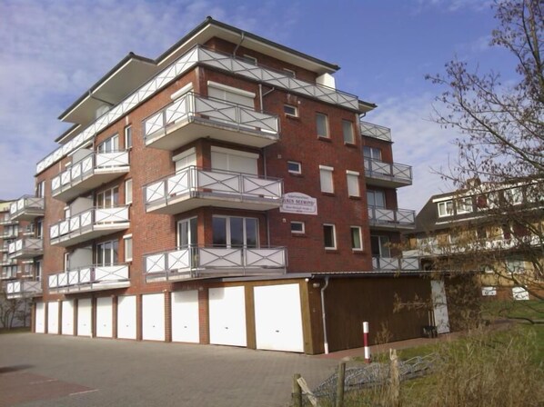 Un edificio residencial de varios pisos con balcones, un garaje y un letrero que indica el nombre "Hals SeeWind".