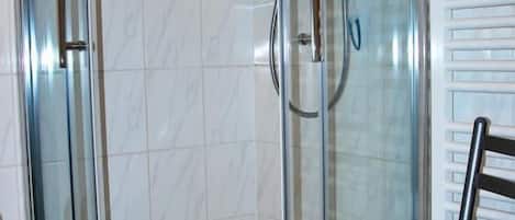 A glass-enclosed shower area with a wooden chair in front.