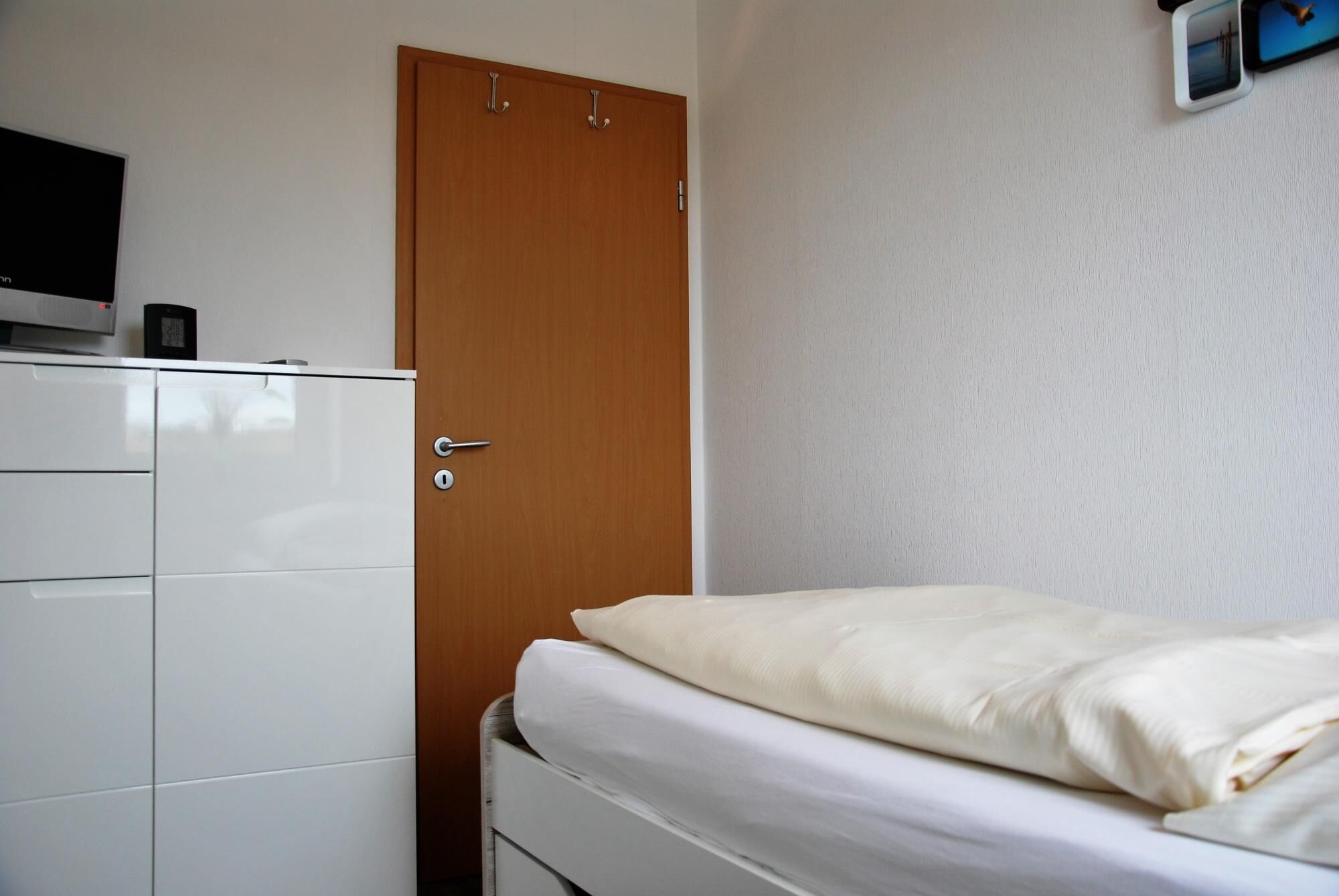 A bedroom with a bed, a wardrobe, and a desk with a computer.