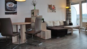 A modern living room with a dining area, a sofa, a coffee table, and a view of the outdoors. - Haus Seewind 10 (Cuxhaven)