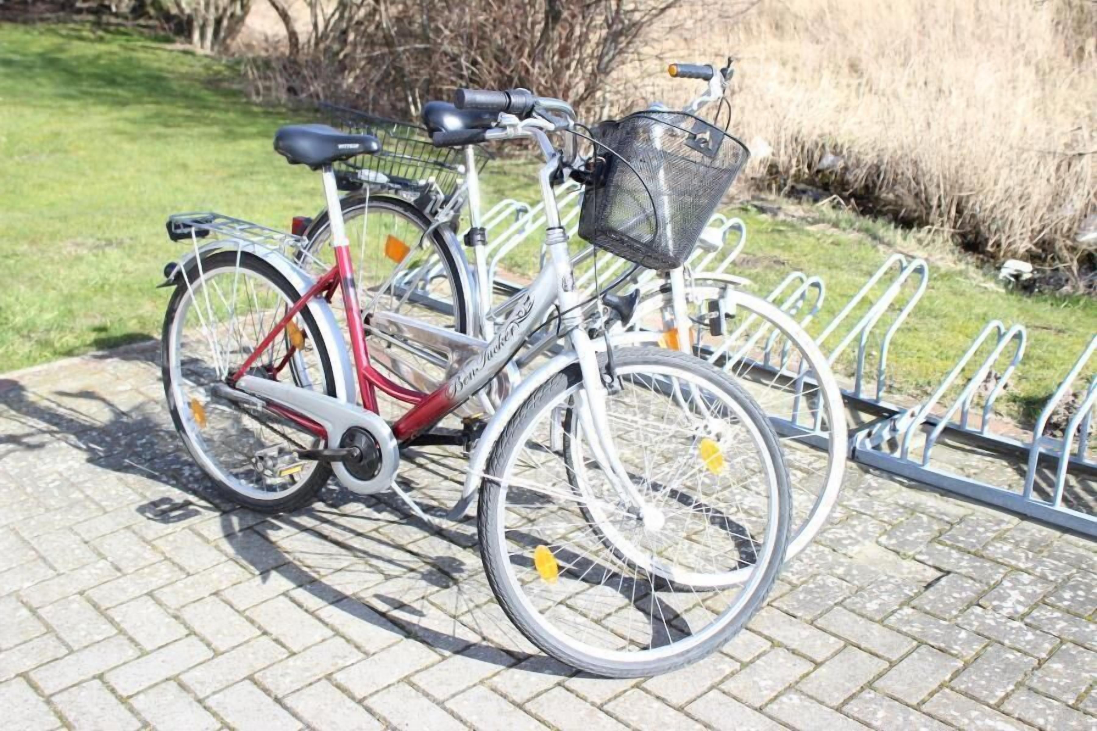 Een fiets geparkeerd op een verhard gebied met een metalen fietsenrek.