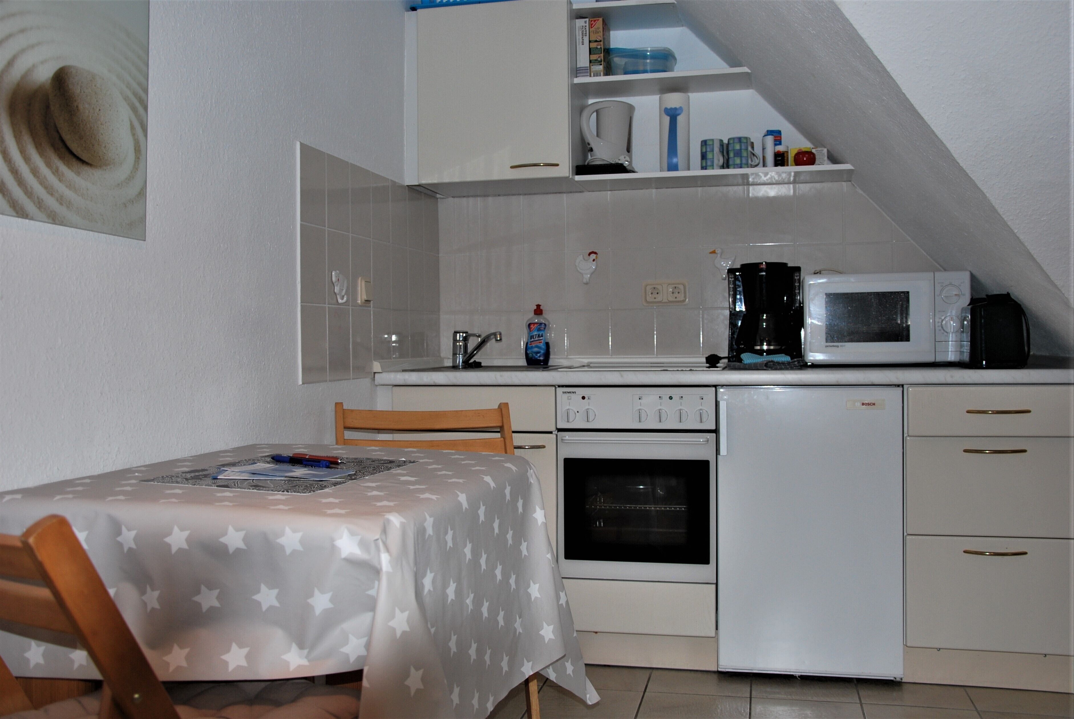 A compact kitchen with a dining table, a microwave, a coffee maker, and a small oven.