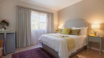 A bedroom with a bed, bedside tables, a desk, a chair, and a window with curtains.