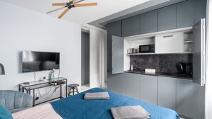 Une chambre moderne équipée d’un lit, d’une télévision, d’un bureau et d’une kitchenette.