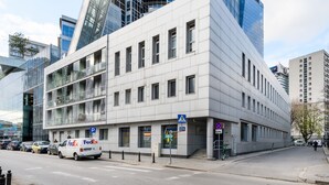 Un bâtiment moderne à la façade blanche, doté de nombreuses fenêtres, avec un fourgon FedEx garé devant.