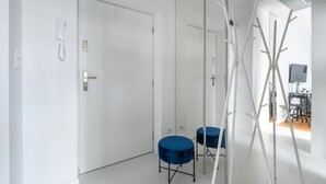 Une pièce moderne avec une porte blanche, une table ronde bleue et une échelle appuyée contre le mur.