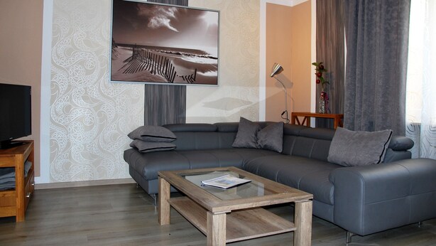Un salon moderne avec un canapé d’angle gris, une table basse en bois et un grand tableau encadré au mur.