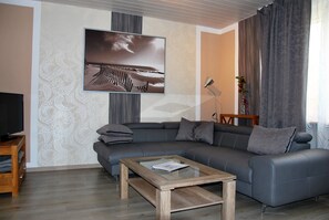Una sala de estar moderna con un sofá seccional gris, una mesa de centro de madera y un cuadro grande en la pared.