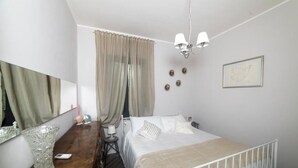Une chambre à coucher avec un lit, une table de chevet, une lampe et un grand miroir.