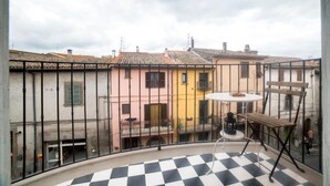 Un balcon avec un sol à carreaux, une table ronde et une chaise.