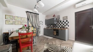 Un espace de vie compact comprenant un coin repas, une cuisine et un tapis à motifs zébrés.