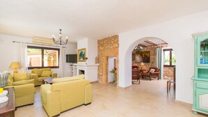 A spacious living area with yellow sofas, a stone fireplace, and a television. - CAN MOLETA  Finca for 8 people near Porto Cristo (Manacor (Porto Cristo))