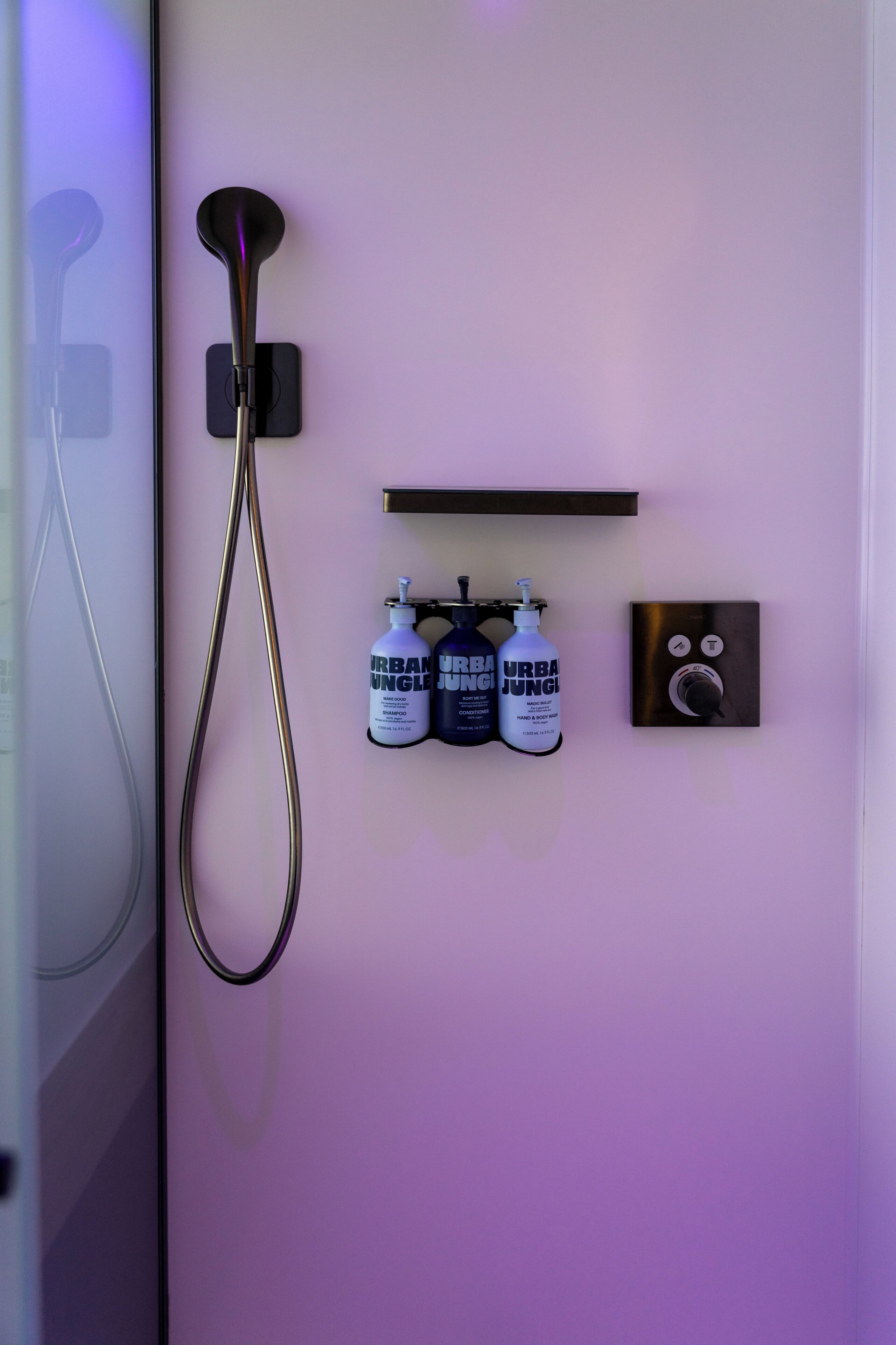 A bathroom with a shower, a soap dispenser, and a hand dryer.
