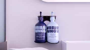 Un baño con una toalla blanca sobre una repisa, un espejo y dos botellas con la etiqueta 'URBAN JUNGLE' sobre una superficie negra.