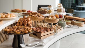 A breakfast buffet with various pastries, bread, and condiments. - YOTEL Porto (Porto)