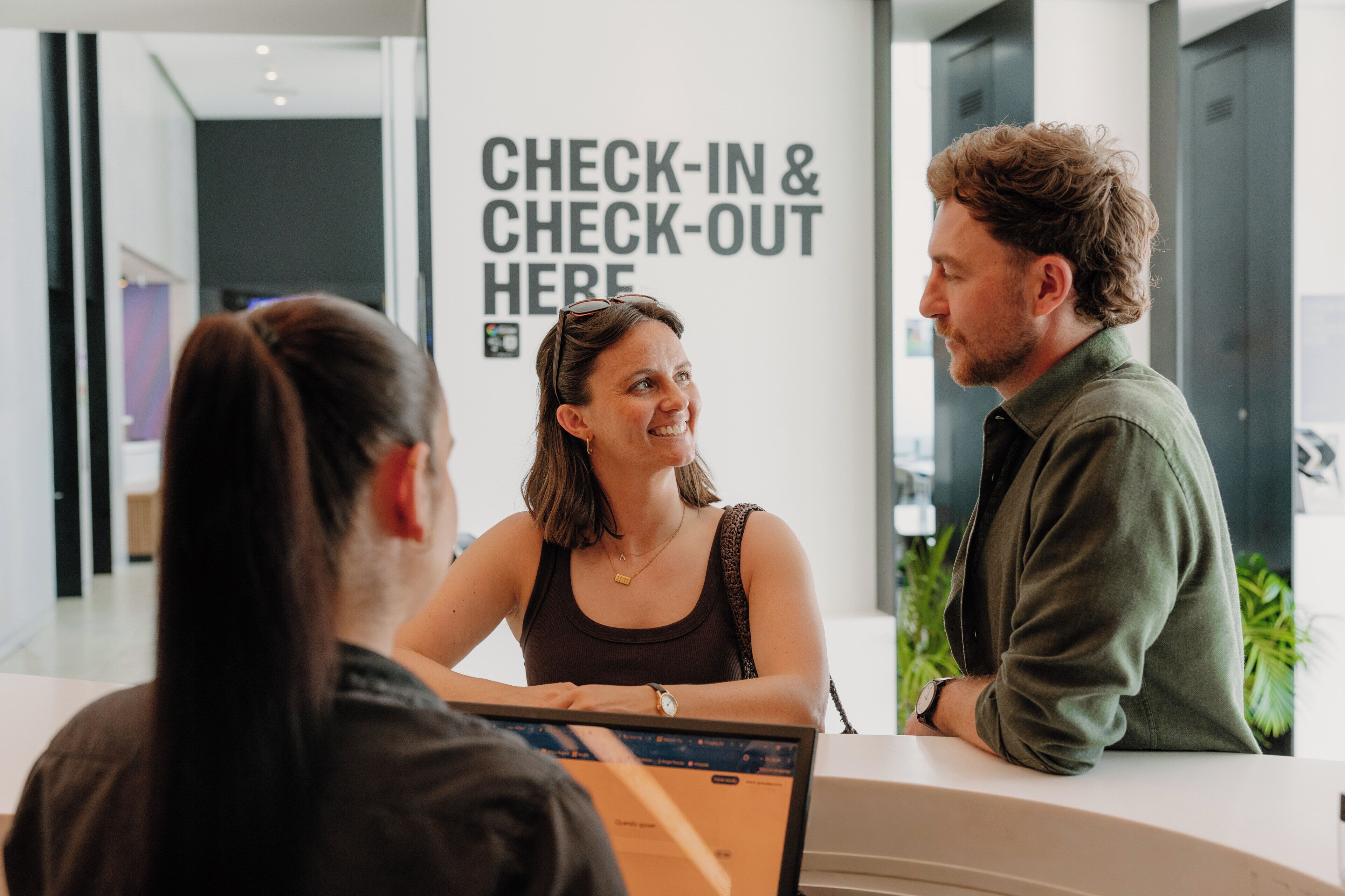A reception desk with a sign that reads 'CHECK-IN & CHECK-OUT HERE'.