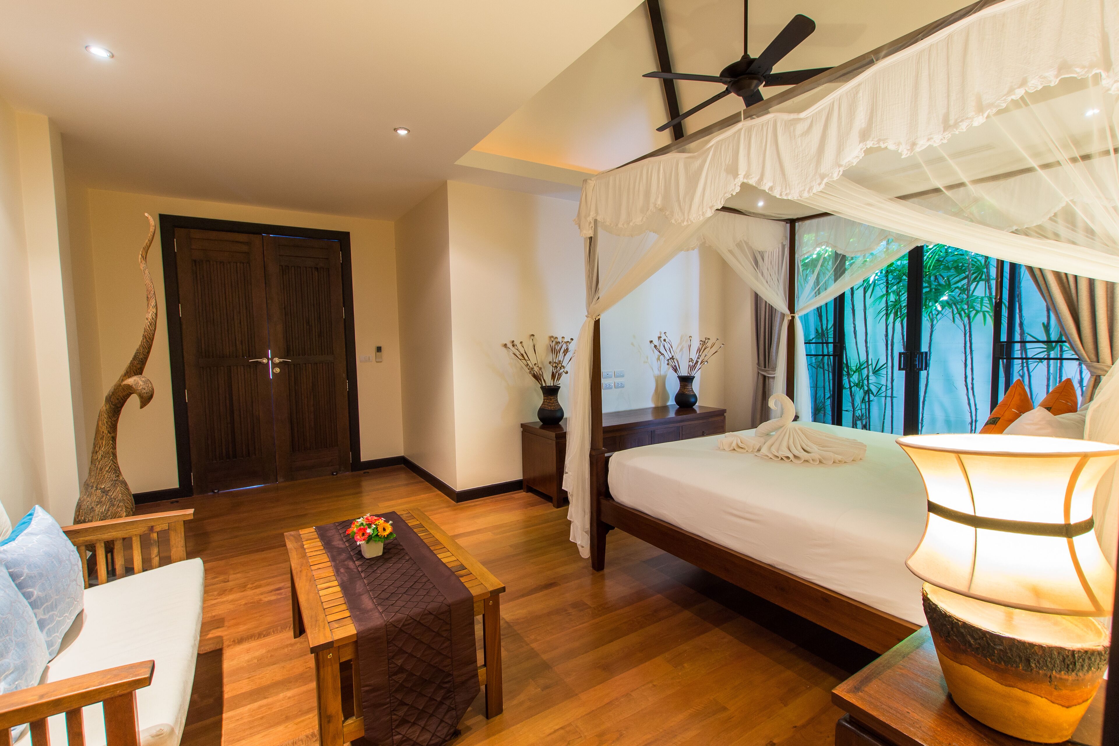 A bedroom with a canopy bed, wooden furniture, and a decorative lamp.