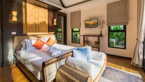 A spacious bedroom with a large bed, a flat-screen TV, and a view of greenery through the windows. - Tulip Pool Villa (Rawai)