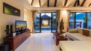 A spacious living room with a large flat-screen TV, wooden entertainment unit, and a sofa. - Tulip Pool Villa (Rawai)