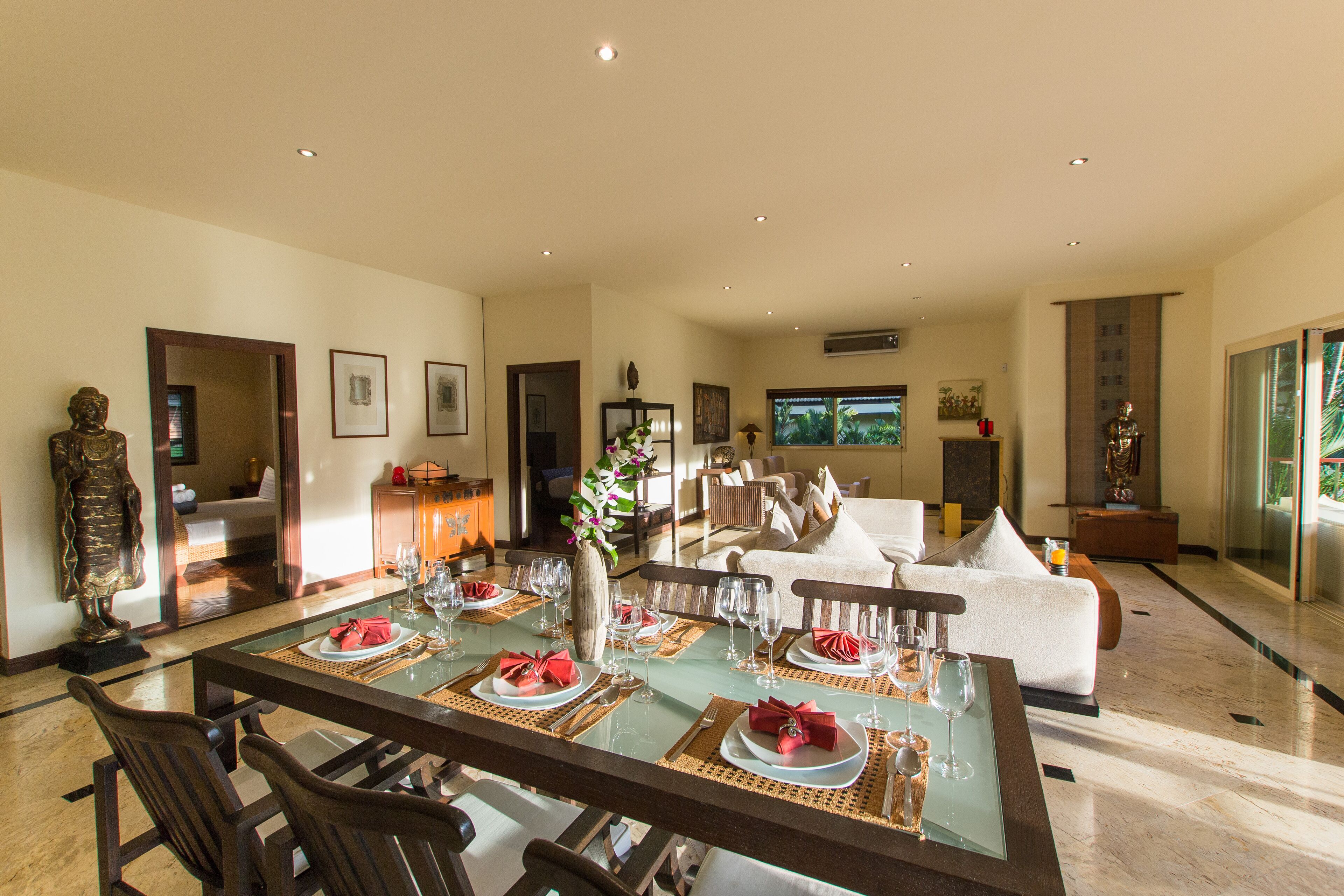 A spacious living area with a dining table set for a meal, a sofa, and a television.
