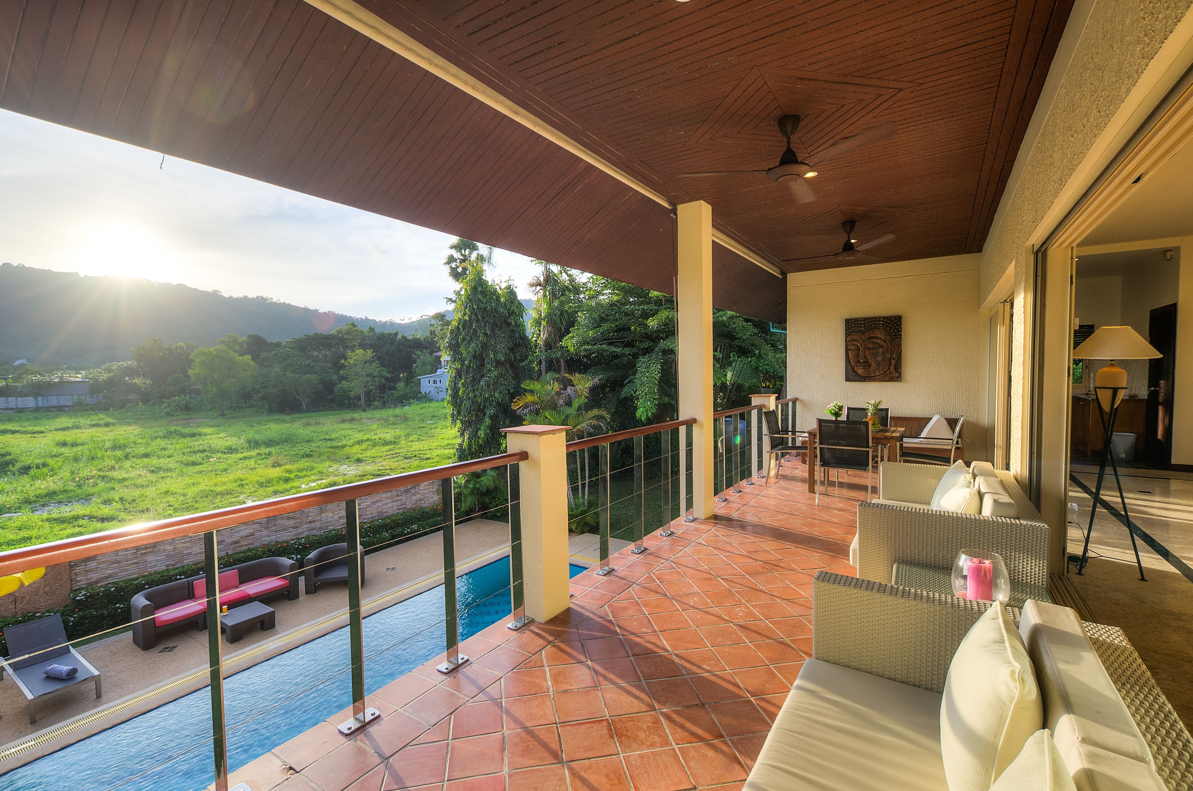 A covered outdoor area with a pool, seating, and a view of the landscape.