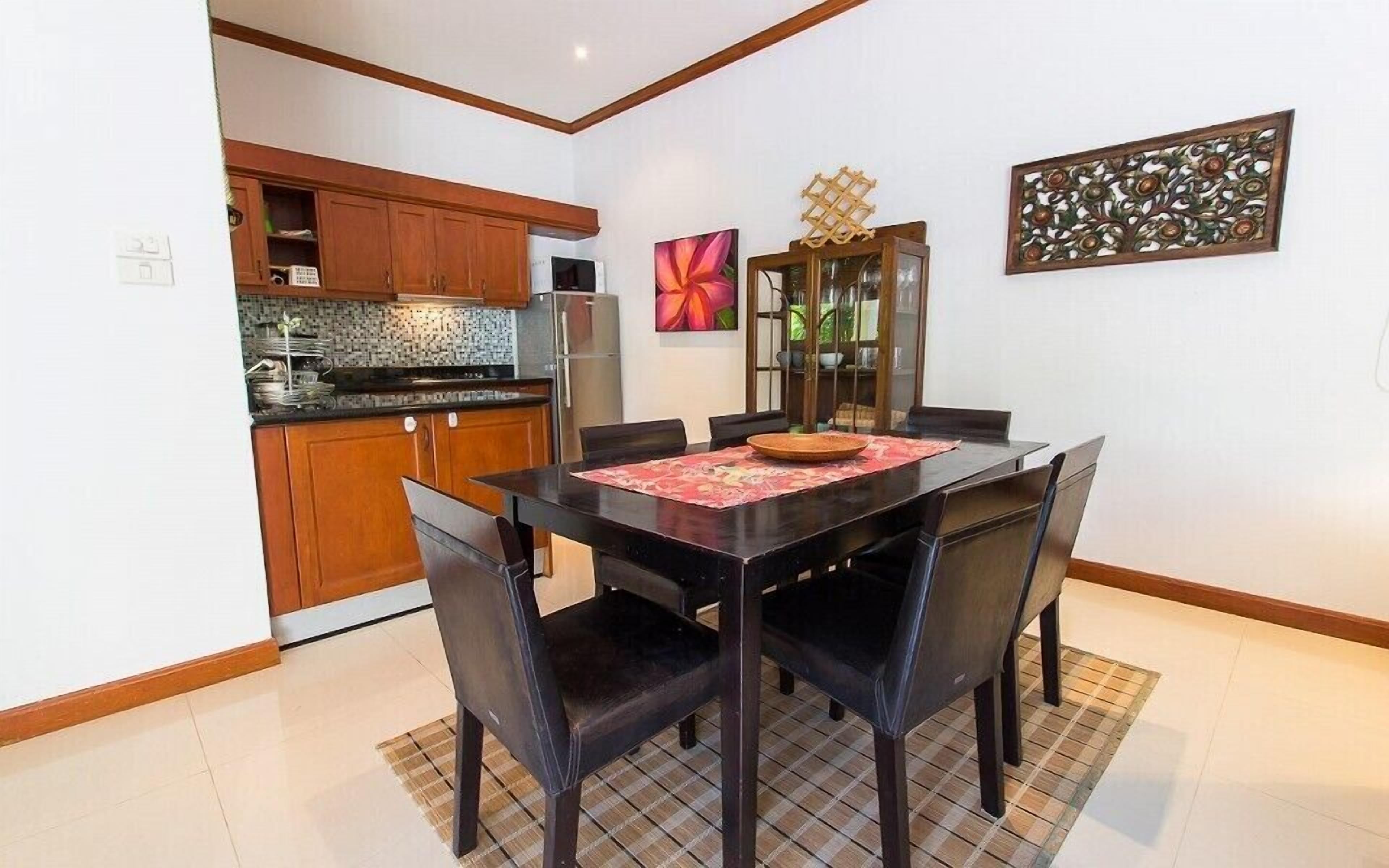 Un coin repas avec une table noire, quatre chaises, un set de table rouge et un bol décoratif.