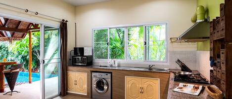 A compact kitchen with a washing machine, a microwave, and a stove.