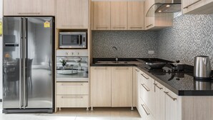Une cuisine moderne dotée d’appareils électroménagers en acier inoxydable, de meubles en bois et d’un revêtement mural en carreaux.
