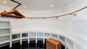 A modern, circular room with white walls and a black floor. It features a wooden hanger, a metal rod, and a wooden crate. - Sky Pool Villa (Rawai)