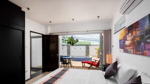A hotel room with a bed, a view of a swimming pool, and a dining area with chairs and a table. - Sky Pool Villa (Rawai)