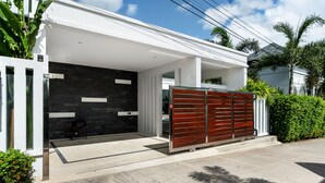 A modern house with a garage, white exterior walls, and a wooden gate. - Crystal Pool Villa (Rawai)