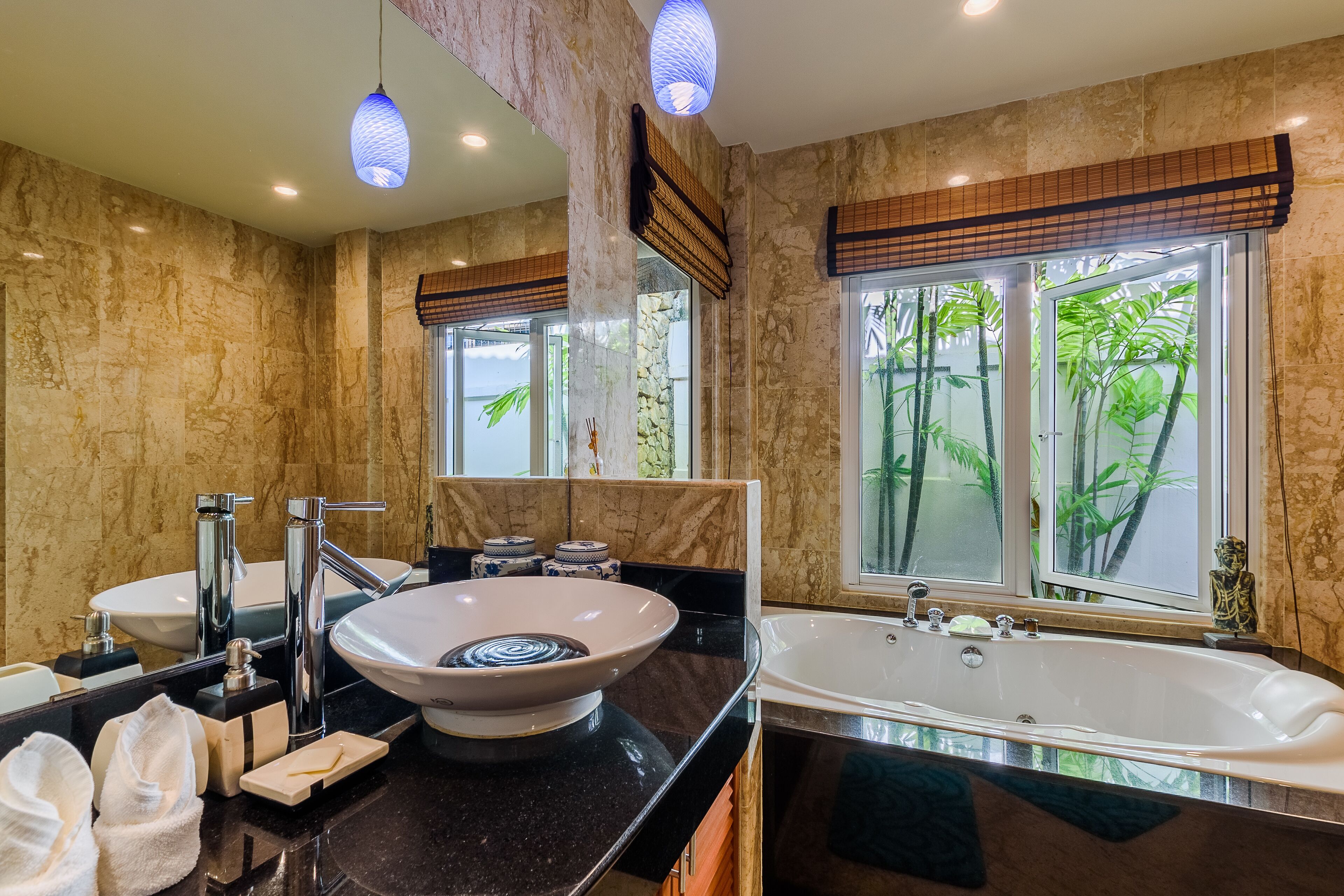 Une salle de bain moderne dotée d’un grand lavabo, d’une baignoire et d’une fenêtre donnant sur un paysage verdoyant.
